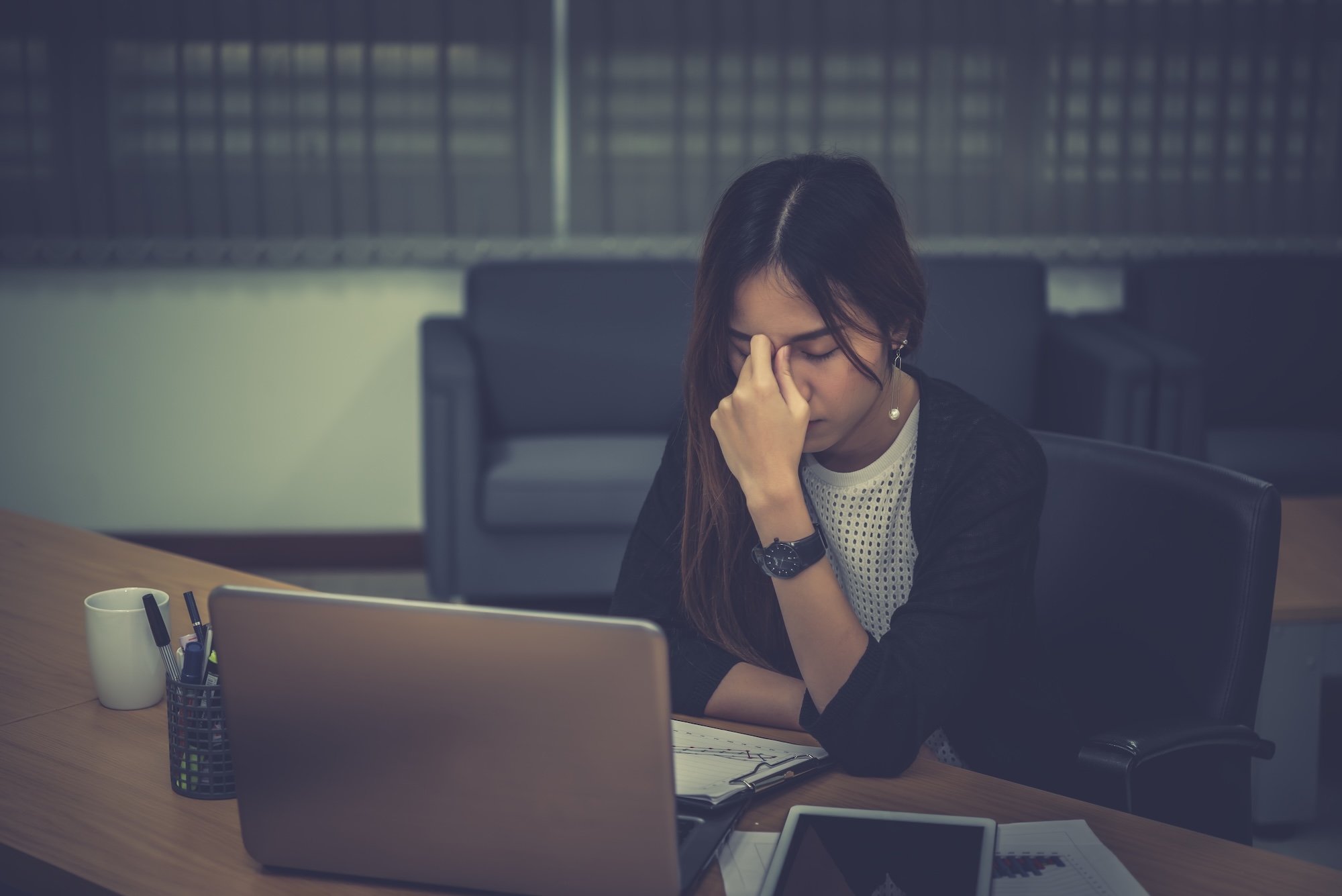 A professional worn down at her desk